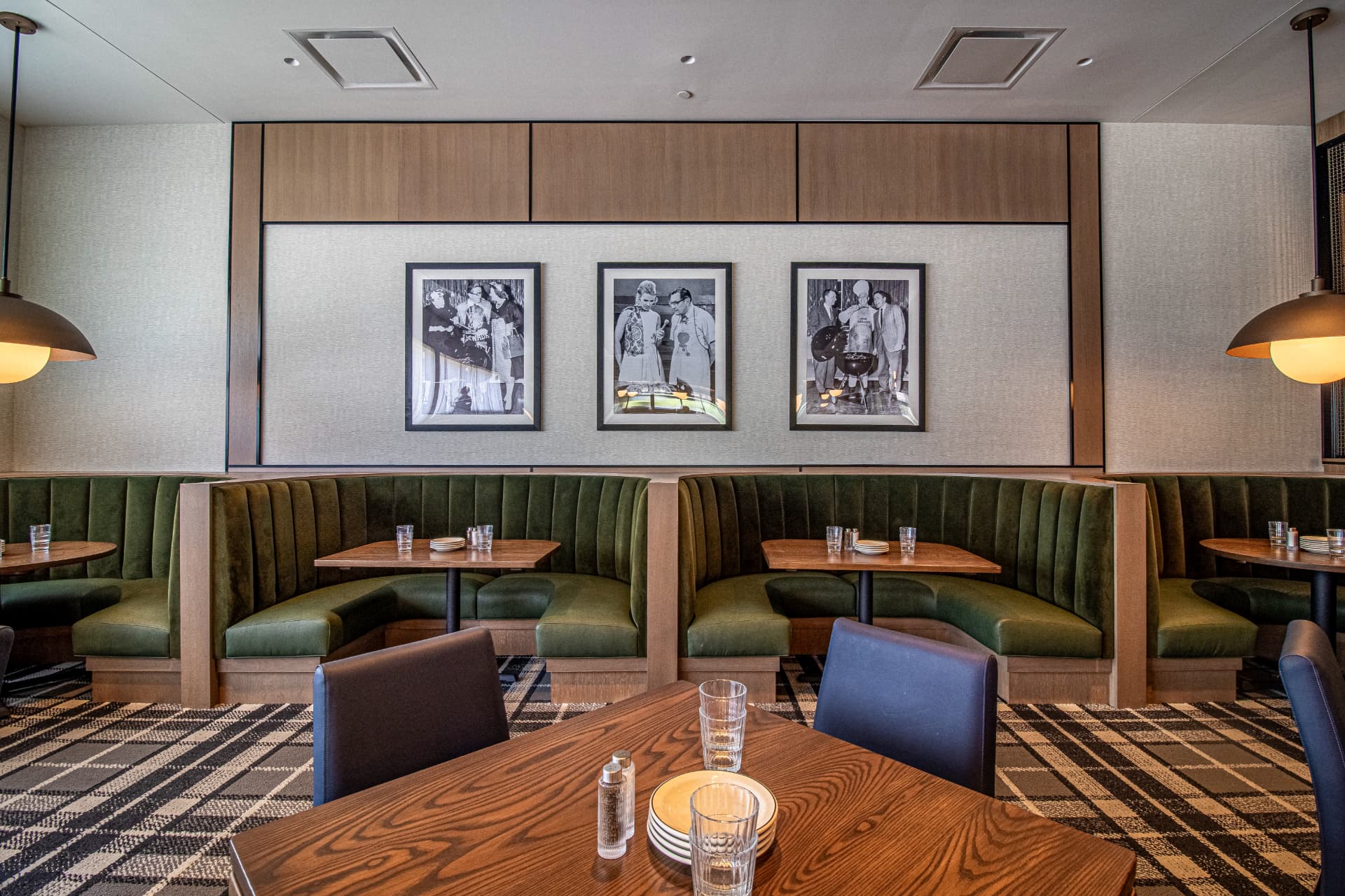 Weber Grill restaurant interior with green velvet banquettes, framed vintage photographs, and warm pendant lighting